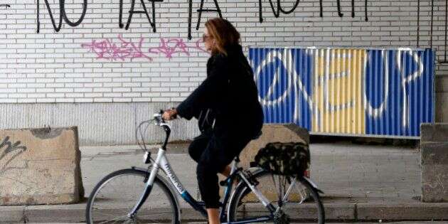 A cyclist rides past graffiti that reads,