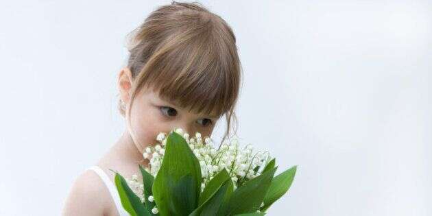 little girl holding bunch of lilies of the valley