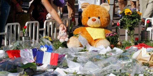 A woman places a stuffed toy alongside flowers, flags and a large stuffed toy in tribute to victims, two days after an attack by the driver of a heavy truck who ran into a crowd on Bastille Day killing scores and injuring as many on the Promenade des Anglais, in Nice, France, July 16, 2016.  REUTERS/Pascal Rossignol