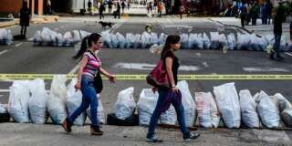 Des femmes traversent une rue bloquée par des manifestants anti-Maduro à Caracas, le 26 juillet.