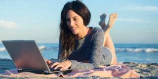 USA, New York State, Rockaway Beach, Woman using laptop on beach