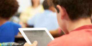 Un élève avec une tablette numérique en classe (illustration)