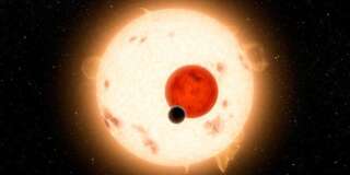 Artist's concept of the Kepler-16 system, showing the binary star being orbited by Kepler-16b. Kepler-16 orbits a slowly rotating K-dwarf that is very active with numerous star spots. Its other parent star is a small red dwarf. The planetary orbital plane is aligned within half a degree of the stellar binary orbital plane.