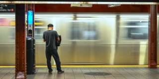 Unrecognizable person waiting as a subway train passes by at high speed creating blurred motion on background in New York City, USA