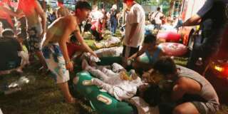 Emergency rescue workers and concert spectators tend to injured victims from an explosion during a music concert at the Formosa Water Park in New Taipei City, Taiwan, Saturday, June 27, 2015. The New Taipei City fire department says 200 people were injured in an accidental explosion of colored theatrical powder Saturday night near a performance stage where about 1,000 people were gathered for party. (AP Photo)    TAIWAN OUT
