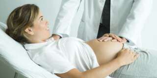 Pregnant woman lying on back, doctor's hand on stomach