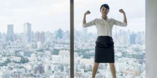 Business woman flexing muscles with city view.