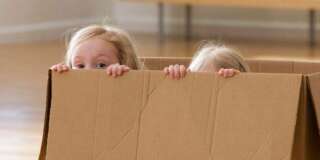 Caucasian sisters playing in cardboard box
