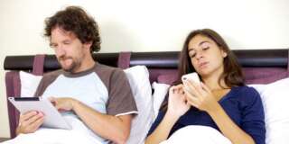man with ipad in bed and woman...