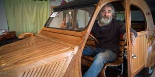 Michel Robillard pose dans sa 2CV construite entièrement à la main et en bois, dans son atelier près de Loches, dans le centre de la France.