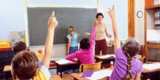 Children with raised hands in classroom