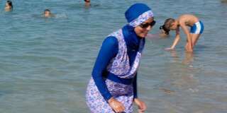 A woman wearing a burkini walks in the water August 27, 2016 on a beach in Marseille, France, the day after the country's highest administrative court suspended a ban on full-body burkini swimsuits that has outraged Muslims and opened divisions within the government, pending a definitive ruling.  REUTERS/Stringer