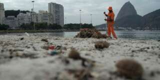 A clean workers removes the trash over the sand of Botafogo beach next to the Sugar Loaf mountain and the Guanabara Bay in Rio de Janeiro, Brazil, Saturday, July 30, 2016. Just days ahead of the Olympic Games the waterways of Rio de Janeiro are as filthy as ever, contaminated with raw human sewage teeming with dangerous viruses and bacteria, according to a 16-month-long study commissioned by The Associated Press.(AP Photo/Leo Correa)