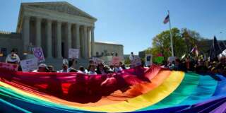 FILE - In this April 28, 2015, file photo, demonstrators stand in front of a rainbow flag of the Supreme Court in Washington, as the court was set to hear historic arguments in cases that could make same-sex marriage the law of the land. Gay and lesbian couples could face legal chaos if the Supreme Court rules against same-sex marriage in the next few weeks. Same-sex weddings could come to a halt in many states, depending on a confusing mix of lower-court decisions and the sometimes-contradictory views of state and local officials. Among the 36 states in which same-sex couples can now marry are 20 in which federal judges invoked the Constitution to strike down marriage bans. (AP Photo/Jose Luis Magana, File)