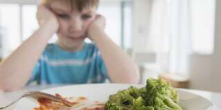 USA, New Jersey, Jersey City, Portrait of boy (4-5) annoyed to eat broccoli