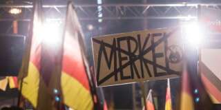 People hold flags and a banner in Erfurt, central Germany, Wednesday, March 16, 2016, during a demonstration initiated by the Alternative for Germany (AfD) party against the immigration situation. The banner shows the strikethrough name of German chancellor Angela Merkel: 'Merkel'. (AP Photo/Jens Meyer)