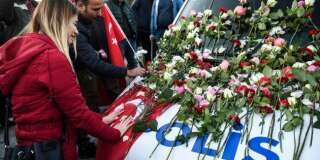 Une femme pleure devant un fourgon de police couvert de fleurs, lors d'un hommage aux victimes de l'attentat devant la Vodafone Arena, le 11 décembre 2016.