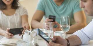 Hispanic friends using cell phones in cafe