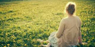Young woman sitting in dandelion field in early spring in rural France.