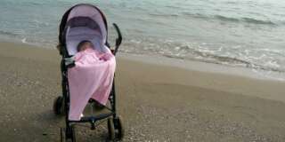 Baby girl in pram on solitary beach.