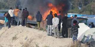 Des migrants devant des tentes incendiées dans la