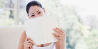 Woman holding book over mouth
