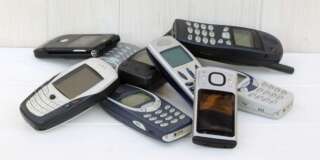 Nine outdated mobile phones stored in pile on shelf.