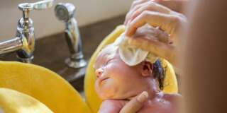 Caucasian newborn baby boy having bath