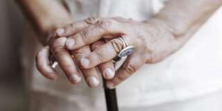 Close-up shot of senior woman's hands holding a crutch.