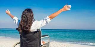 Disabled woman with arms outstretched at the beach on a sunny day