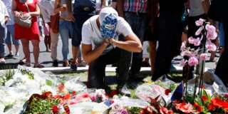 A man reacts near bouquets of flowers as people pay tribute near the scene where a truck ran into a crowd at high speed killing scores and injuring more who were celebrating the Bastille Day national holiday, in Nice, France, July 15, 2016.   REUTERS/Pascal Rossignol