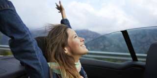 Young woman riding on the backseat of car on mountain road