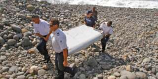 In this photo dated Wednesday, July 29, 2015, French police officers carry a piece of debris from a plane in Saint-Andre, Reunion Island. Air safety investigators, one of them a Boeing investigator, have identified the component as a 