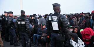 Des policiers surveillent la foule de migrants attendant d'être évacuée de la