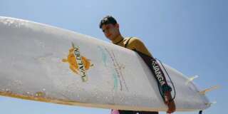 Ali Kassem, 17 ans, réfugié syrien, avec sa planche de surf sur une plage de la ville de Jiyeh, dans le sud du Liban.