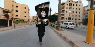 A member loyal to the Islamic State in Iraq and the Levant (ISIL) waves an ISIL flag in Raqqa June 29, 2014. The offshoot of al Qaeda which has captured swathes of territory in Iraq and Syria has declared itself an Islamic