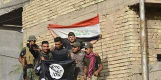 Iraqi security forces raise an Iraqi flag as they hold a flag of the Islamic State group they captured in central Fallujah, Iraq, after fighting against the Islamic State militants,  Friday, June 17, 2016. Iraqi special forces entered the center of Fallujah city early Friday, taking over a government complex and a neighborhood that served as a base for the Islamic State group militants after intense fighting. (AP Photo)