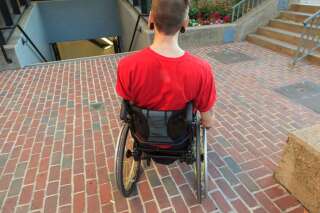 Un homme handicapé devant une bouche de métro impraticable en fauteuil roulant.