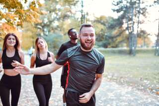 Smiling Male Helping Motivate Jogging Multi Ethnic Friends In Park