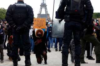 Des manifestants protestent genou à terre devant des policiers et gendarmes lors d'une manifestation au Champ de Mars, à Paris le 6 juin 2020, dans le cadre des manifestations mondiales 