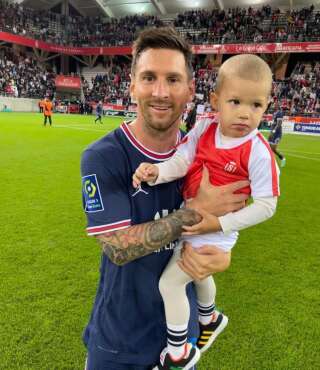 Lionel Messi pose avec le fils du gardien rémois Predrag Rajković le 29 août 2021 à l'issue du match Reims-PSG.
