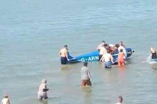 Des baigneurs sortent un pilote de son avion écrasé sur la plage