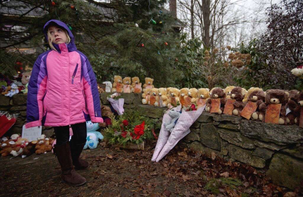 Sandy Hook Elementary School Shooting - Ava Staiti, 7, of New Milford, Conn., looks up at her mother Emily Staiti, not pictured, while visiting a sidewalk memorial with 26 teddy bears, each representing a victim of the Sandy Hook Elementary School shooting, Sunday, Dec. 16, 2012, in Newtown, Conn. A gunman walked into Sandy Hook Elementary School in Newtown Friday and opened fire, killing 26 people, including 20 children. (AP Photo/David Goldman)