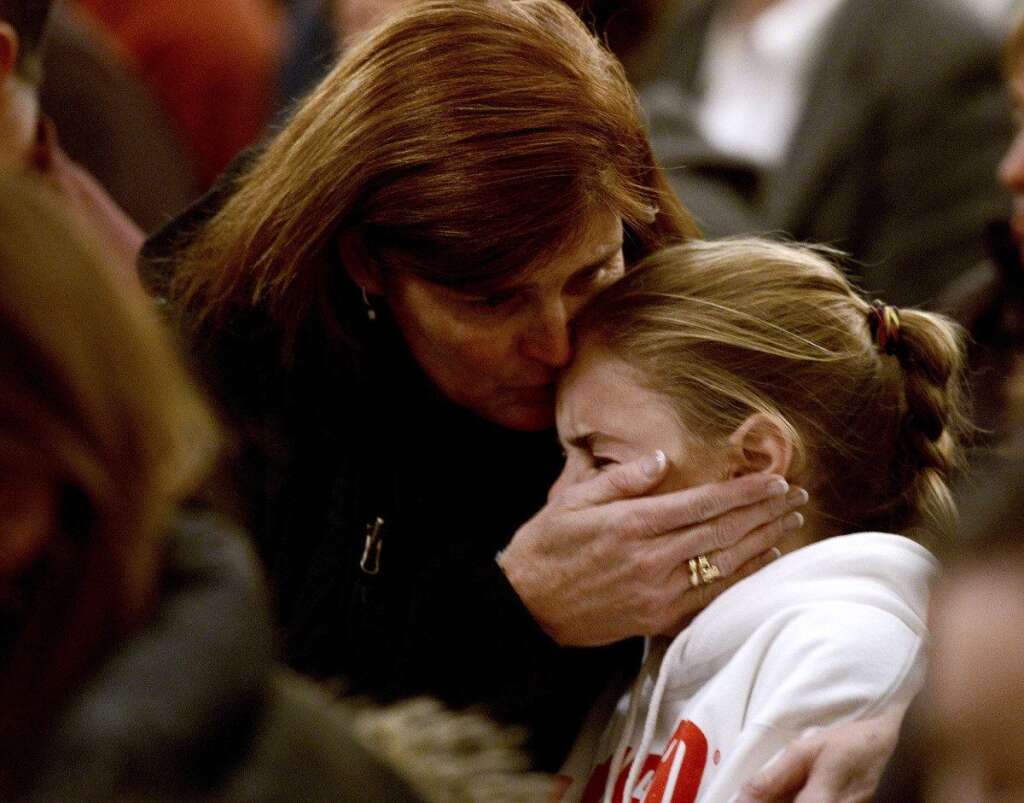 Sandy Hook Elementary School Shooting - A woman comforts a young girl during a vigil service for victims of the Sandy Hook Elementary shooting, Friday, Dec. 14, 2012, at St. Rose of Lima Roman Catholic Church in Newtown, Conn. (AP Photo/Andrew Gombert, Pool)