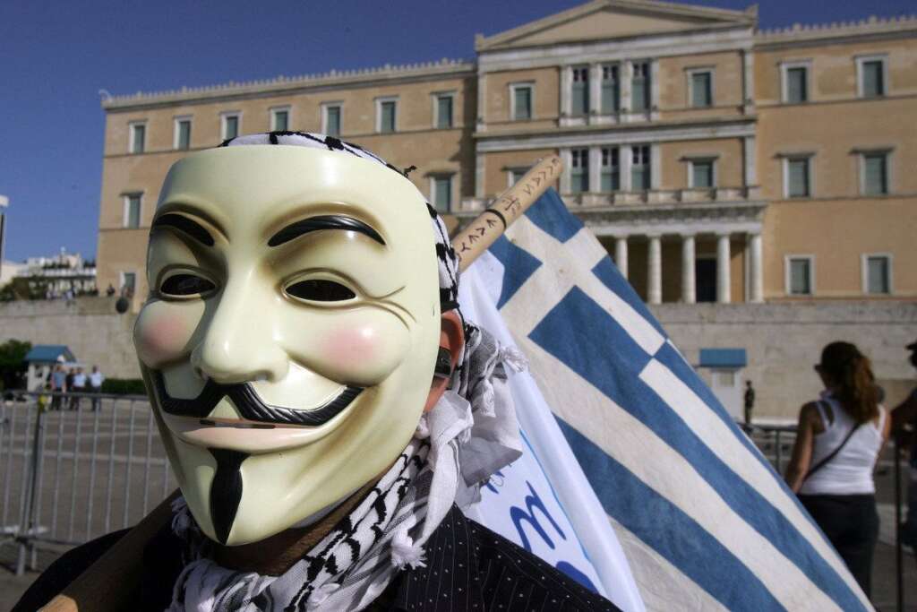 Greece Crippled By General Strike - ATHENS, GREECE - OCTOBER 18:  A protester wears a Guy Fawkes mask in front of the Greek Parliament bulding during a 24-hour nationwide general strike on October 18, 2012 in Athens, Greece. Hundreds of youths pelted riot police with petrol bombs, bottles and chunks of marble today as yet another Greek anti-austerity demonstration descended into violence.  (Photo Milos Bicanski/Getty Images)