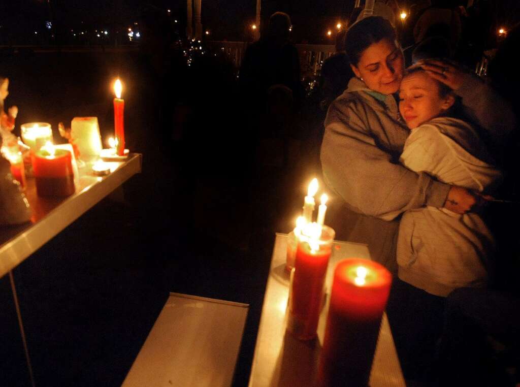 Sandy Hook Elementary School Shooting - Brenda Hernadez of Enfield Conn., comforts her daughter Crystal at a makeshift shrine on the Enfield Town Green, Friday evening, December 14, 2012, after a candlelight vigil in Enfield, Conn. The vigil was organized by social media in memory of the school shooting victims in Newtown as residents in Enfield, 70 miles from Newtown, and in through out the state, feel the grief of the mass shooting at the Sandy Hook Elementary School Friday morning. (AP Photo/Journal Inquirer, Jim Michaud)