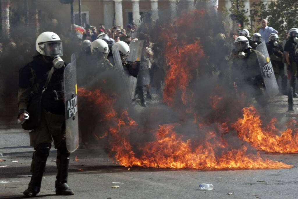Greece Crippled By General Strike - ATHENS, GREECE - OCTOBER 18:  Protesters throw petrol bombs at riot police officers during a 24-hour nationwide general strike on October 18, 2012 in Athens, Greece. Hundreds of youths pelted riot police with petrol bombs, bottles and chunks of marble today as yet another Greek anti-austerity demonstration descended into violence.  (Photo Milos Bicanski/Getty Images)