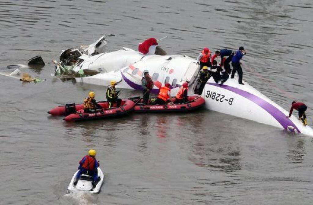 Emergency personnel approach a commercial plane after it crashed in Taipei, Taiwan, Wednesday, Feb. 4, 2015. The Taiwanese commercial flight with 58 people aboard clipped a bridge shortly after takeoff and crashed into a river in the island's capital of Taipei on Wednesday morning. (AP Photo) TAIWAN OUT