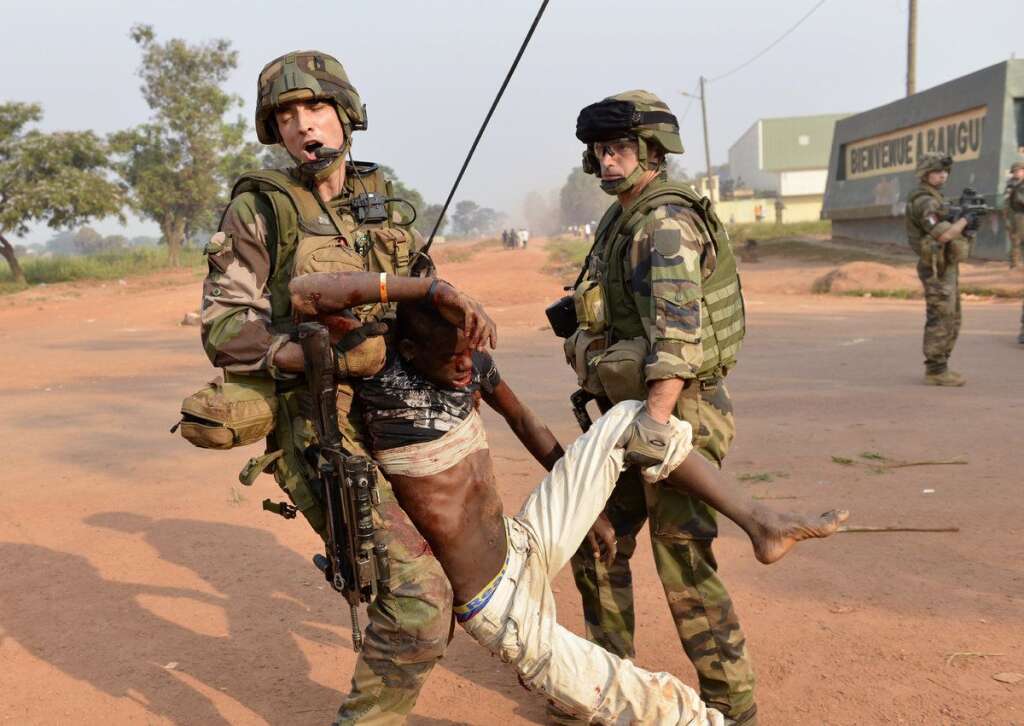 VUE PAR L'AFP - Si l'armée française insiste sur l'aide médicale délivrée par les troupes, elle fait néanmoins l'impasse sur les échanges de tirs parfois nourris qui opposent ses soldats aux rebelles. Ici, deux soldats français évacuent le cadavre d'un manifestant abattu aux alentours de l'aéroport de Bangui, le 23 décembre 2013.