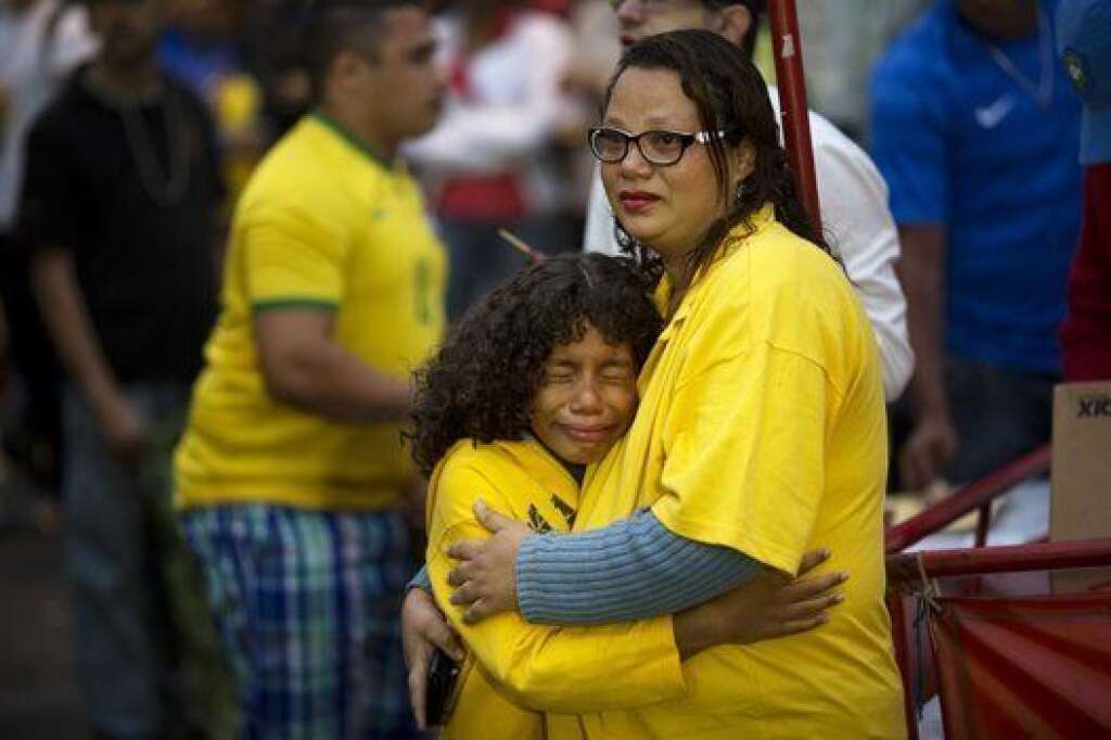 Brazil WCup Soccer Brazil Germany - Brazil soccer fans embrace as they watch their team lose to Germany via a live telecast of the World Cup semifinal game in Sao Paulo, Brazil, Tuesday, July 8, 2014. (AP Photo/Rodrigo Abd)